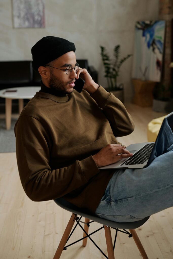 Young man multitasking at home using laptop and smartphone for remote work.